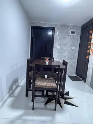 a wooden table with a chair and a black door at Beit Al Hasan بيت الحسن in Um Qeis