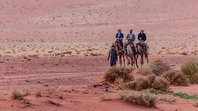 a group of people riding horses in the desert at WhyDesert Camp & Tours in Wadi Rum
