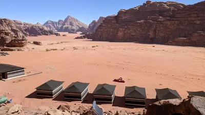 a group of tents in a desert with mountains at WhyDesert Camp & Tours in Wadi Rum