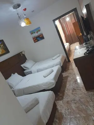 a room with three beds and a desk in it at Karam Inn in Aqaba