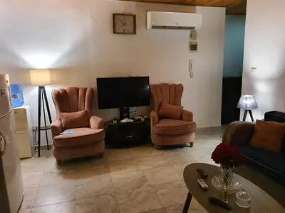 a living room with two chairs and a flat screen tv at Suad Apartment in Amman