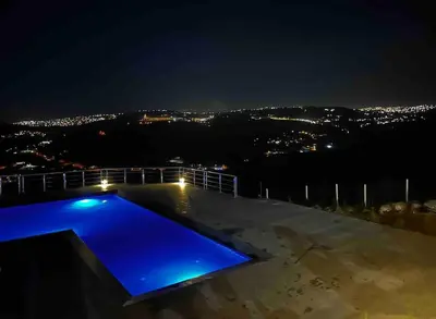 a swimming pool at night with a view of a city at Farmhouse with Pool and Breathtaking Views in Amman