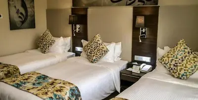 a hotel room with three beds and a phone at شقق المومني in Amman