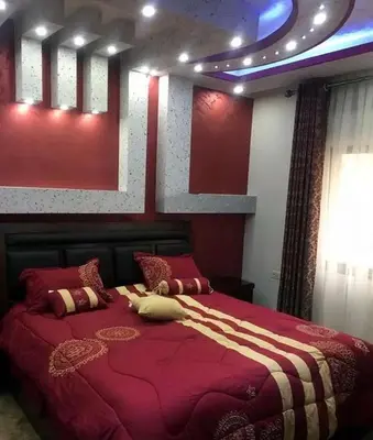 a bedroom with a large bed with a red bedspread at شقق المومني in Amman