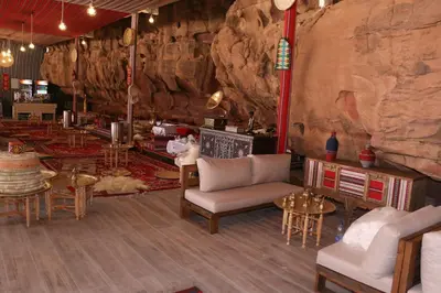 a room with chairs and tables and a rock wall at Imagination Luxury Camp in Disah
