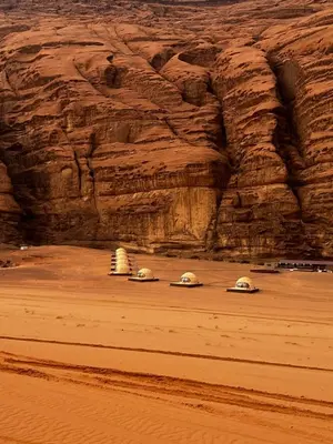 three domes in the desert near a rock wall at Golden Gate Luxury Camp in Wadi Rum