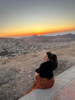 a woman sitting on the ground looking at the sunset at Petra Anas House in Wadi Musa