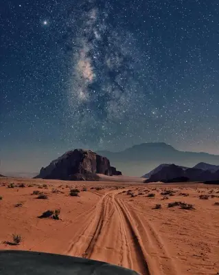 a dirt road in the desert under a starry sky at wadi rum tha moon in Wadi Rum