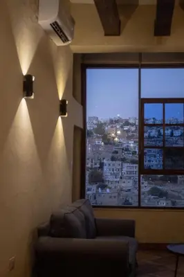a living room with a couch and a large window at Saraya locanda in Al Salt