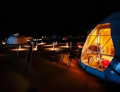 a tent with a table and chairs at night at Shebara Camp Wadi Rum in Wadi Rum