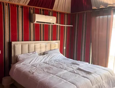 a bed in a bedroom with a red wall at Shebara Camp Wadi Rum in Wadi Rum