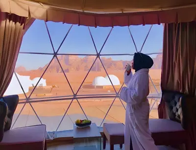 a woman talking on a cell phone in front of a window at Shebara Camp Wadi Rum in Wadi Rum