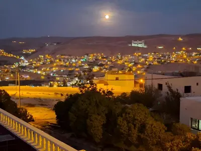 a view of a city at night with the moon at Marvel Hotel Apartments in Wadi Musa
