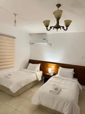 a bedroom with two beds and a chandelier at Marvel Hotel Apartments in Wadi Musa