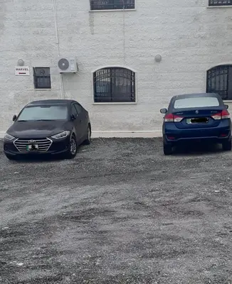 two cars parked in a parking lot next to a building at Marvel Hotel Apartments in Wadi Musa