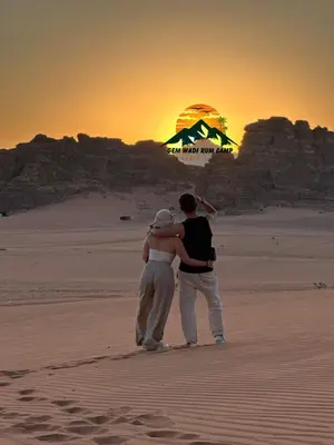 a man and woman standing on the beach at sunset at Gem wadi rum camp in Wadi Rum