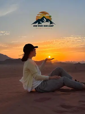 a woman sitting in the desert watching the sunset at Gem wadi rum camp in Wadi Rum