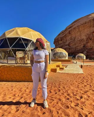 a woman standing in the sand in front of a building at Rum Plaza Luxury Camp in Wadi Rum