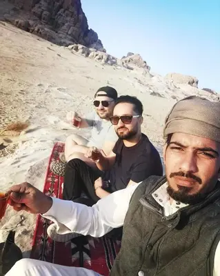 a group of three men sitting on the beach at Rum Plaza Luxury Camp in Wadi Rum