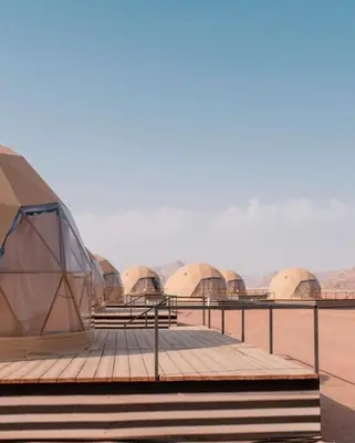 a group of domes in a desert with mountains in the background at Rum Plaza Luxury Camp in Wadi Rum