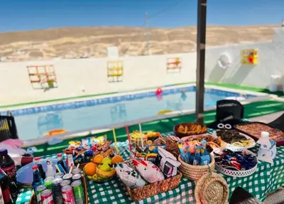a table with baskets of food next to a pool at Little Green Farm in Wadi Musa