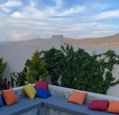 a row of colorful pillows sitting on a bench near the water at Little Green Farm in Wadi Musa