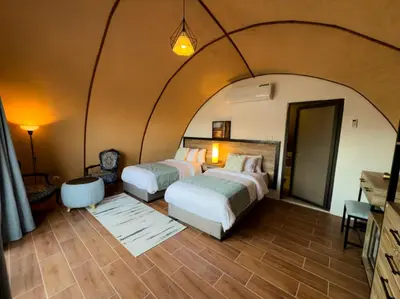 two beds in a bedroom with an arched ceiling at Shell Luxury Camp in Wadi Rum