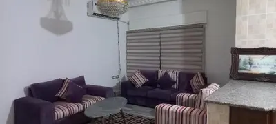 a living room with two purple couches and a counter at Khalda Apartments for females in Amman