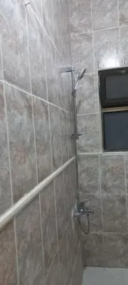 a shower in a bathroom with a stone wall at Khalda Apartments for females in Amman
