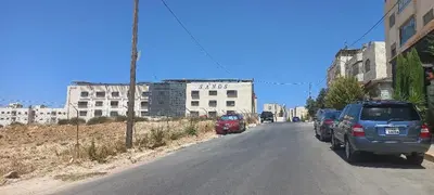 a street with cars parked on the side of a building at Khalda Apartments for females in Amman