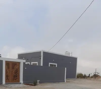 a gray building with a wooden door in front of it at مزرعة الشفق in Ad Dimnah