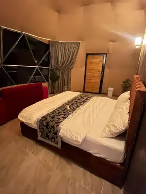 a bedroom with a large bed with a wooden headboard at Madar Camp, Wadi Rum in Wadi Rum