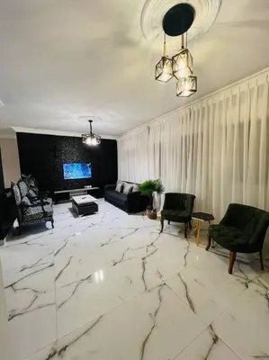 a living room with a marble floor with chairs and a couch at Luxury 4-bedrooms apartment in Aqaba
