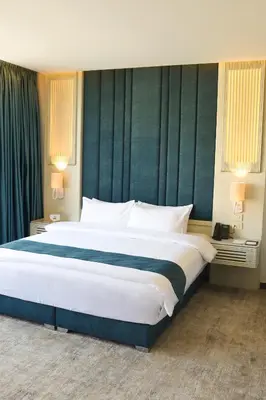 a bedroom with a large white bed with green walls at Rival Hotel Amman in Amman