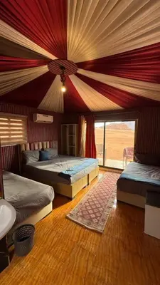 a bedroom with two beds and a large window at Wadi Rum Santa Camp in Wadi Rum