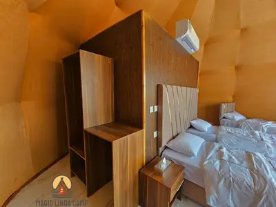 a bedroom with a bed and a wooden cabinet at wadi rum,Linda Camp in Wadi Rum
