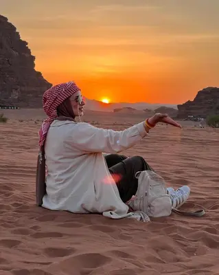 a woman sitting in the desert watching the sunset at wadi rum,Linda Camp in Wadi Rum