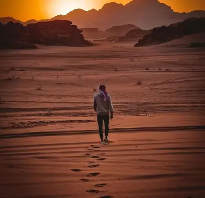 a man walking on the desert with footprints in the sand at Joker camp Wadi Rum in Disah