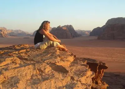 a woman sitting on a rock in the desert at Joker camp Wadi Rum in Disah