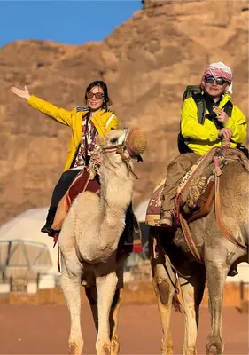 a man and a woman riding on the back of a camel at The bubble camp in Wadi Rum
