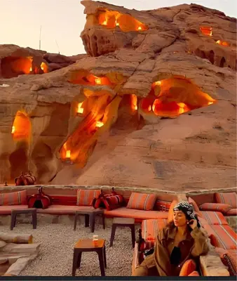 a woman sitting on a couch in front of a rock wall at The bubble camp in Wadi Rum