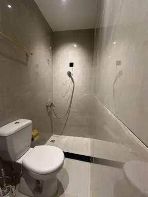a white bathroom with a toilet and a shower at Aladnan hotel in Aqaba