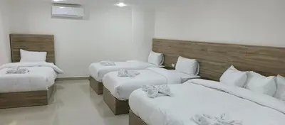 a room with three beds with white sheets at Petra Desert Hotel in Wadi Musa