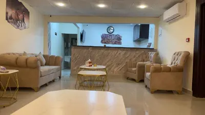 a living room with couches and tables and a clock at Petra Desert Hotel in Wadi Musa