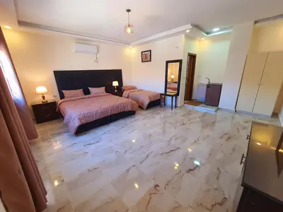 a bedroom with two beds and a marble floor at iHome Petra in Wadi Musa