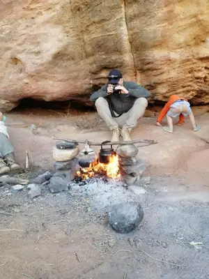 a man taking a picture of a camp fire at - Trekking from Dana to Petra in Dana