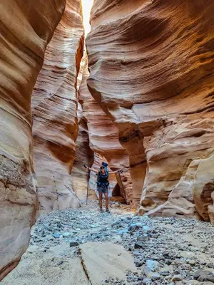 a person standing in a slot canyon at - Trekking from Dana to Petra in Dana