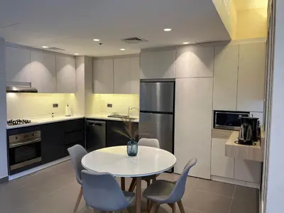 a kitchen with a table and chairs and a refrigerator at DAMAC Luxury new 1 bedroom apartment in Amman