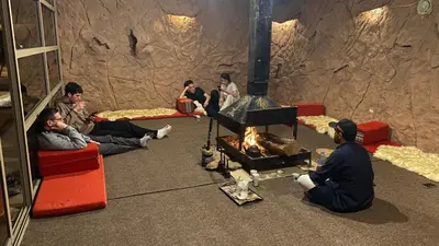 a group of people sitting around a fire in a cave at Wadi Rum Desert Bedouins in Wadi Rum