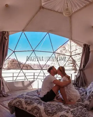a man and woman sitting on a bed in a tent at Angelina Luxury Camp in Wadi Rum